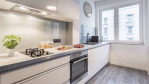 A modern kitchen with a gas stove, oven, and a window with a view of buildings.