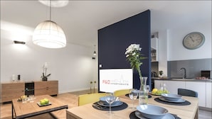A modern dining area with a wooden table set for four, a vase with flowers, and a sign for P&O Apartments.