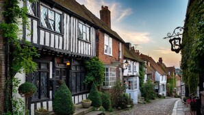 A cobblestone street lined with traditional half-timbered houses, stone steps, and a small garden with potted plants. - Stream House Luxury B&B (Hastings)