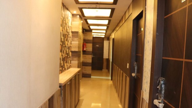 A hotel hallway with a wooden floor, a reception desk, and a door with a handle. - Hotel Angina (Kolkata)