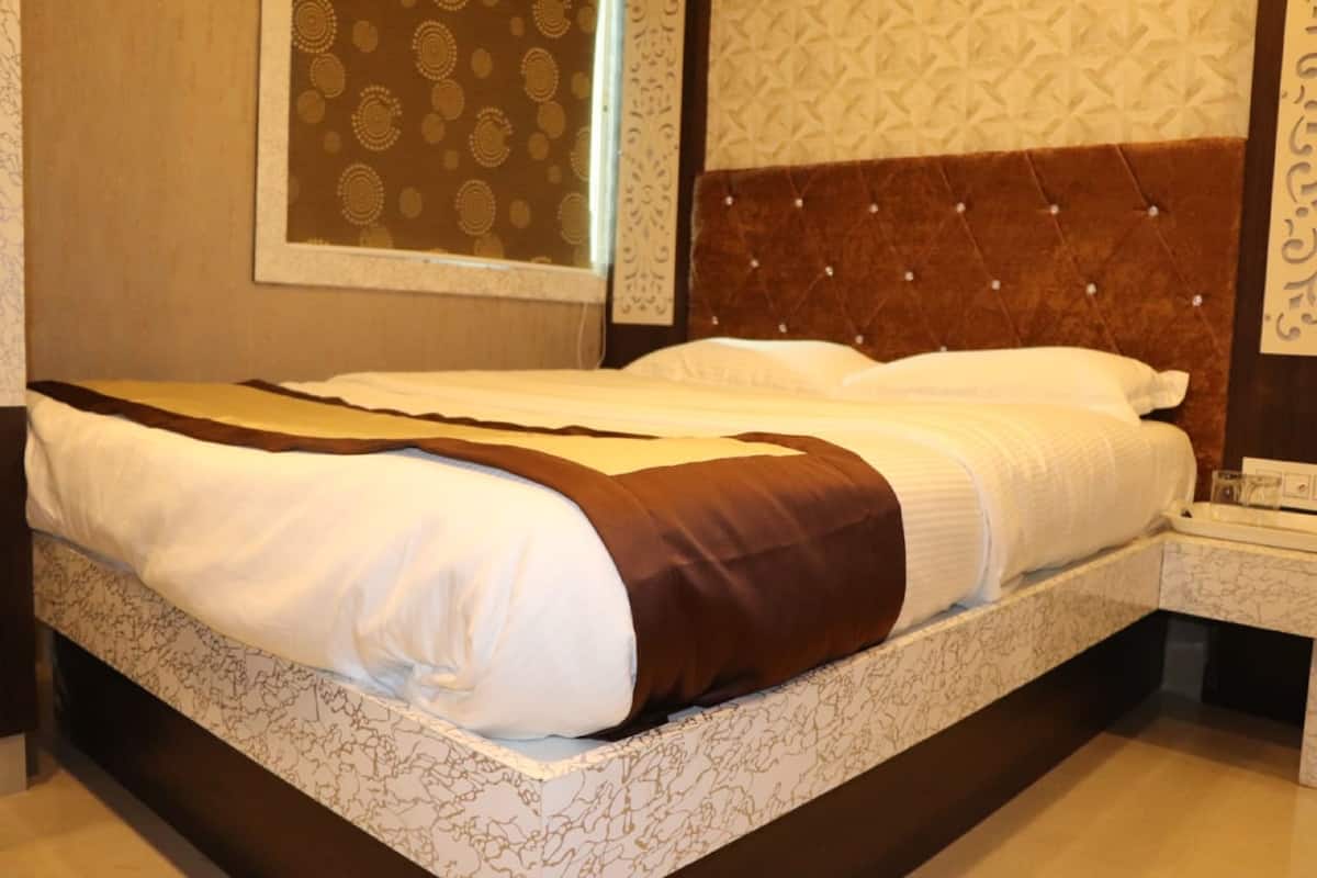 Una cama bien tendida con un cabecero estampado y una mesita de noche con una lámpara.