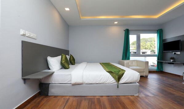 A modern bedroom with a bed, a TV, and a window with curtains. - Treebo Apple Villa (Bengaluru)