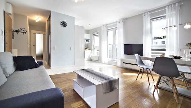 Un salon moderne comprenant un canapé, une table basse et un coin repas avec des chaises.
