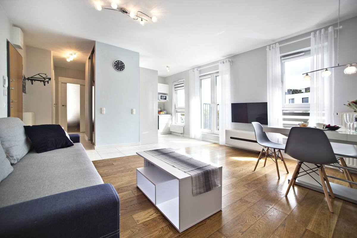 Een moderne woonkamer met een bank, een salontafel, en een eethoek met stoelen.