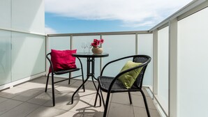 A balcony with two chairs, a small round table, and a vase with flowers.