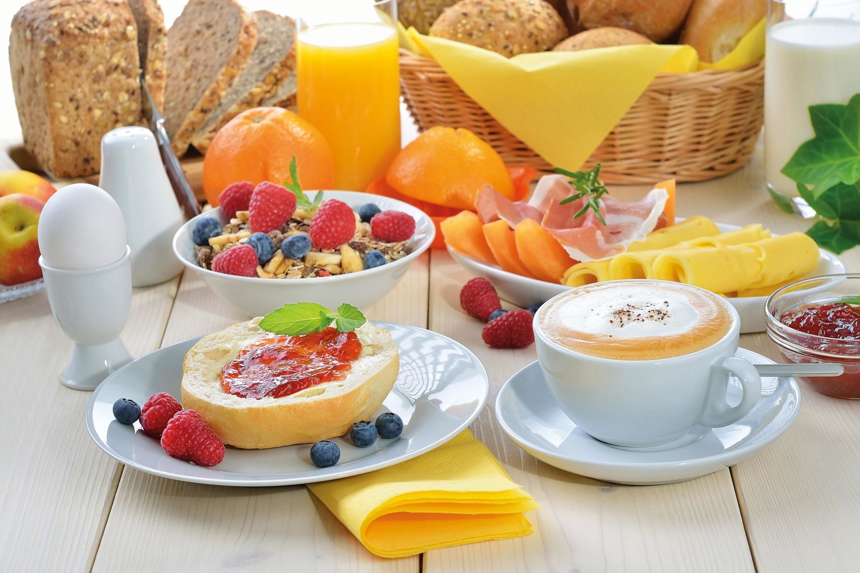 A breakfast setting with bread, fruits, cheese, and a cup of coffee.