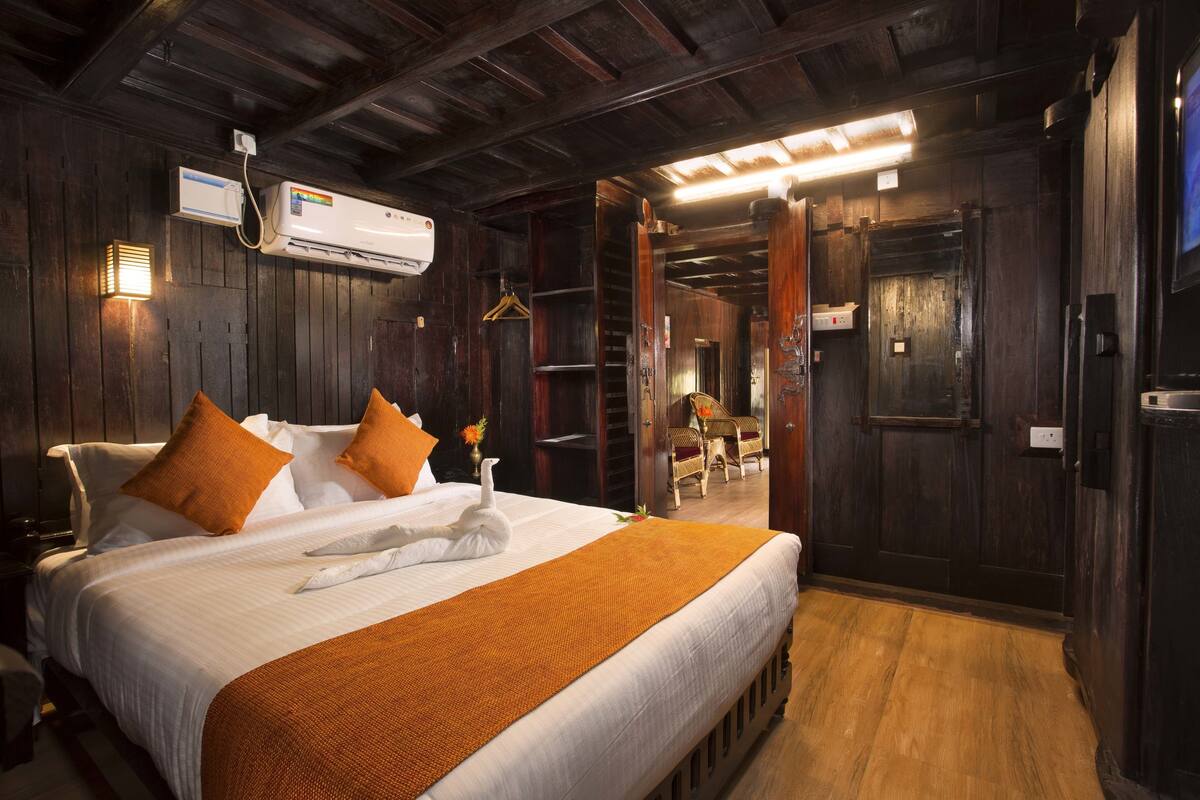 Quarto de hotel com uma cama grande, paredes de madeira e um ar condicionado moderno.