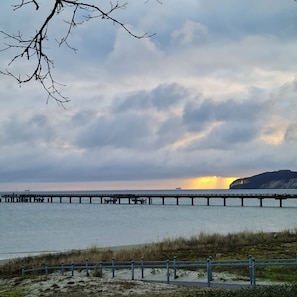 Un muelle se adentra en aguas tranquilas con un atardecer de fondo.