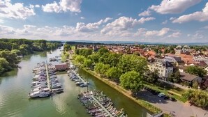 A riverside town with a marina, historic buildings, and a prominent church tower. - Villa Rhenus (Ginsheim-Gustavsburg)