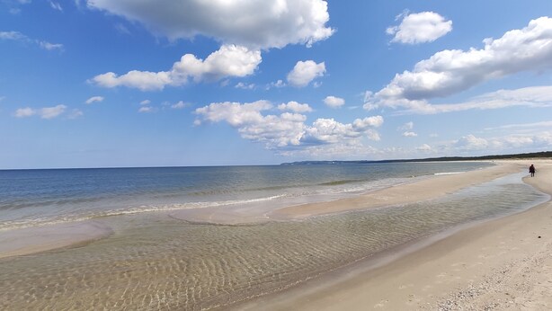 A beach with clear water, a sandy shore, and a person walking. - karsibor.de (Swinoujscie)