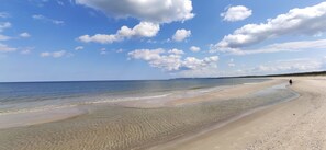 A beach with clear water, a sandy shore, and a person walking. - karsibor.de (Swinoujscie)
