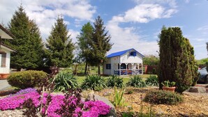 A small house with a blue roof, surrounded by a garden with various plants and flowers. - karsibor.de (Swinoujscie)