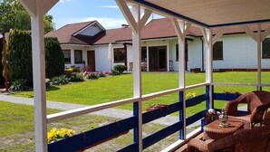 A covered patio area with wicker furniture and a view of a house with a red roof. - karsibor.de (Swinoujscie)