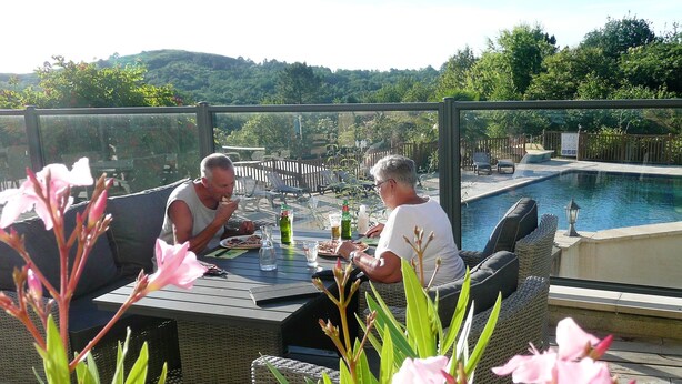 Comedor con mobiliario exterior, vistas a una piscina y colinas.