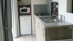 Una cocina compacta con microondas, estufa, fregadero y un refrigerador pequeño.