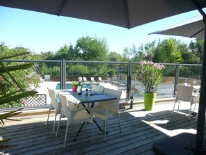 Un patio techado al aire libre con mesa de billar, sillas y una mesa dispuesta para comer.