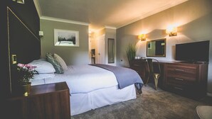 Een slaapkamer met een bed, een kaptafel, een televisie en een spiegel.