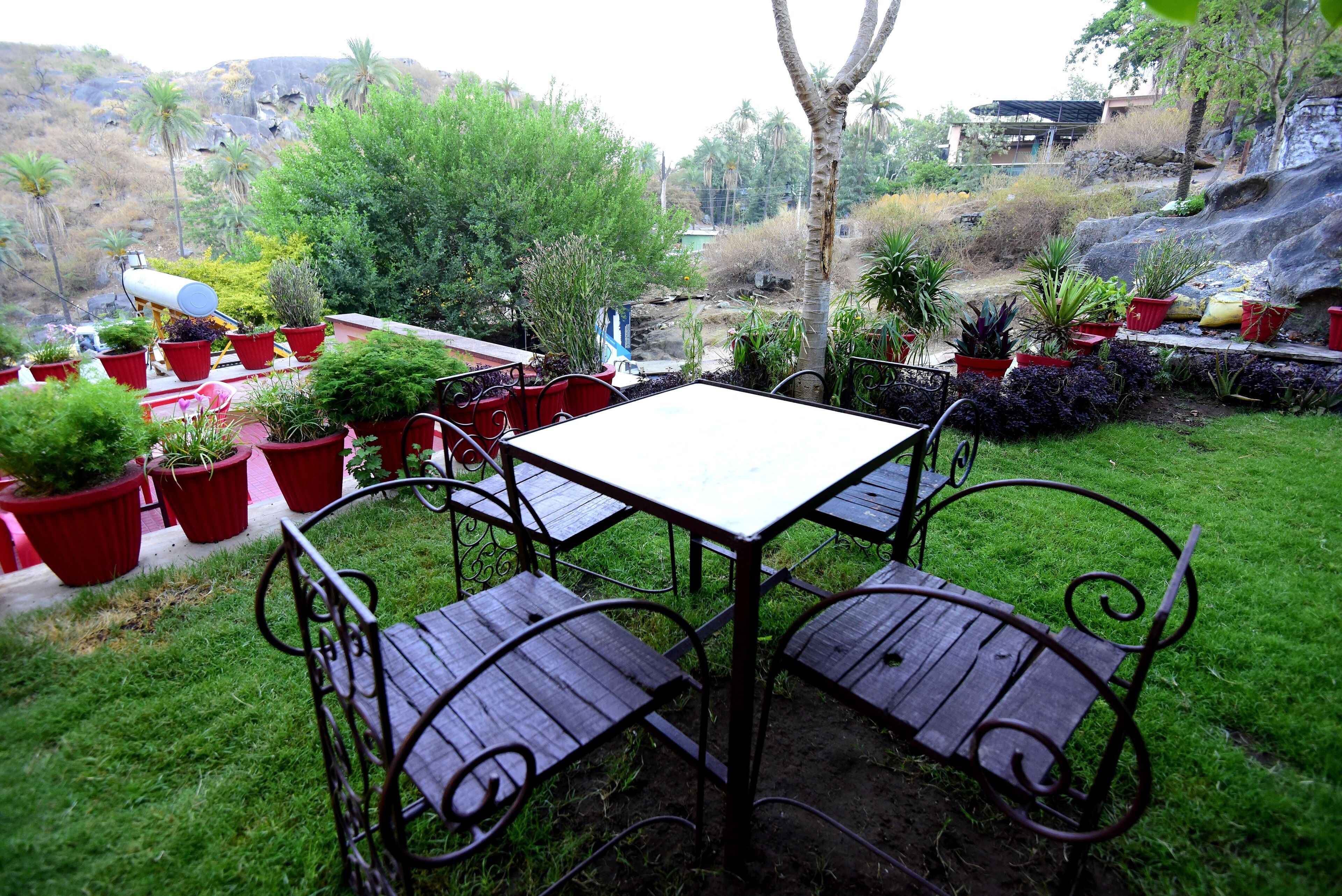 A patio with a table and chairs, surrounded by potted plants.