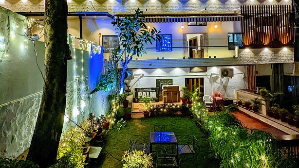 An outdoor patio area with potted plants, a table, and chairs. - Eminence - Palm Residency (Abu Road)
