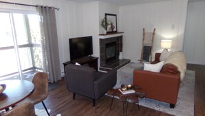 A living room with a TV, fireplace, sofa, and dining area. - Blue River Condos 3 Bed 2 Bath (Breckenridge)