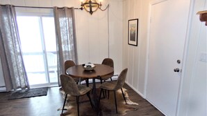 A dining area with a round table, four chairs, a chandelier, a framed picture on the wall, and a fur rug on the floor. - Blue River Condos 3 Bed 2 Bath (Breckenridge)