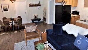 A compact living space with a dining area, a sofa, a kitchen with wooden cabinets, and a refrigerator. - Blue River Condos 3 Bed 2 Bath (Breckenridge)