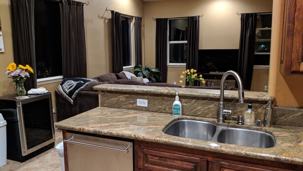 A compact kitchen with a granite countertop, double sink, and wooden cabinets. - Pokerville Retreat in the Heart of Amador Wine Country (Plymouth)