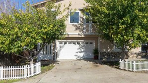 A two-story house with a garage, surrounded by a white picket fence, and trees in front. - Pokerville Retreat in the Heart of Amador Wine Country (Plymouth)