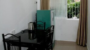 A dining area with a table and chairs, a ceiling fan, a window with curtains, and a view of greenery outside. - Bamba Flat (Colombo)