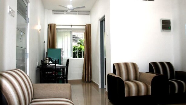 A modern living room with a sofa, armchairs, a dining table, and a ceiling fan. - Bamba Flat (Colombo)