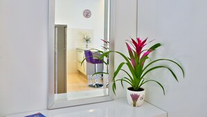 Un baño con lavamanos blanco, un espejo y una planta en maceta.