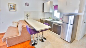 Una cocina moderna con comedor, que incluye un sofá, taburetes de bar y un refrigerador.
