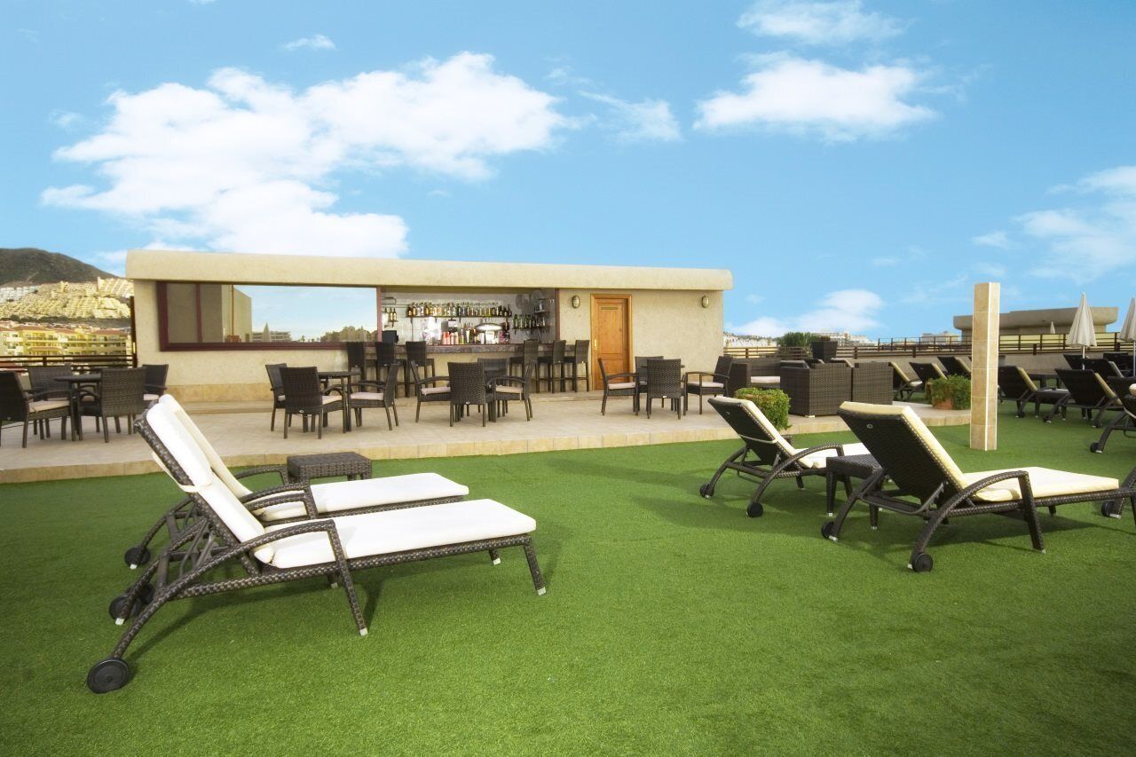 An outdoor seating area with chairs and tables, a bar, and a view of the city.