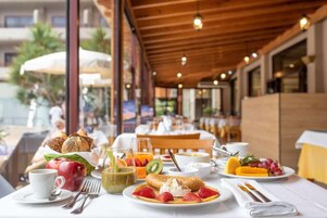 A breakfast setting with a variety of foods, including fruits, pastries, and beverages, arranged on a table with a white tablecloth.