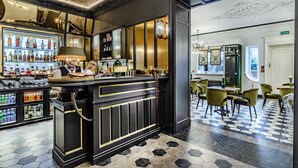 Un espace bar comprenant un comptoir, des étagères remplies de bouteilles et un coin salon avec des chaises.