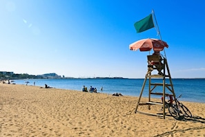 A lifeguard station with a flag and umbrella on a sandy beach.