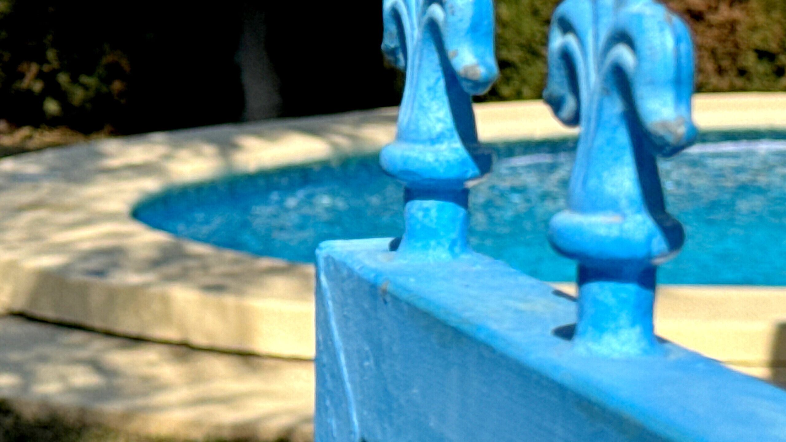 A close-up of a blue fountain with a decorative top.
