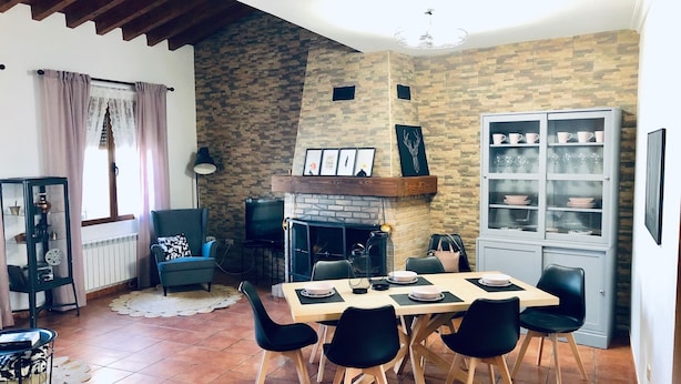 A dining area with a stone wall, a fireplace, and a cabinet with dishes. - La Barraca de Culón (Cañada Juncosa)
