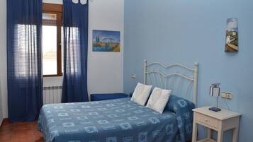 A bedroom with a bed, a bedside table, and a window with curtains.