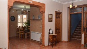 A spacious living area with a dining table and chairs, a kitchen area with a fridge and a stove, and a staircase leading to an upper floor. - La Barraca de Culón (Cañada Juncosa)