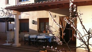 A patio with outdoor seating, a bicycle, and a tree with blossoms. - La Barraca de Culón (Cañada Juncosa)