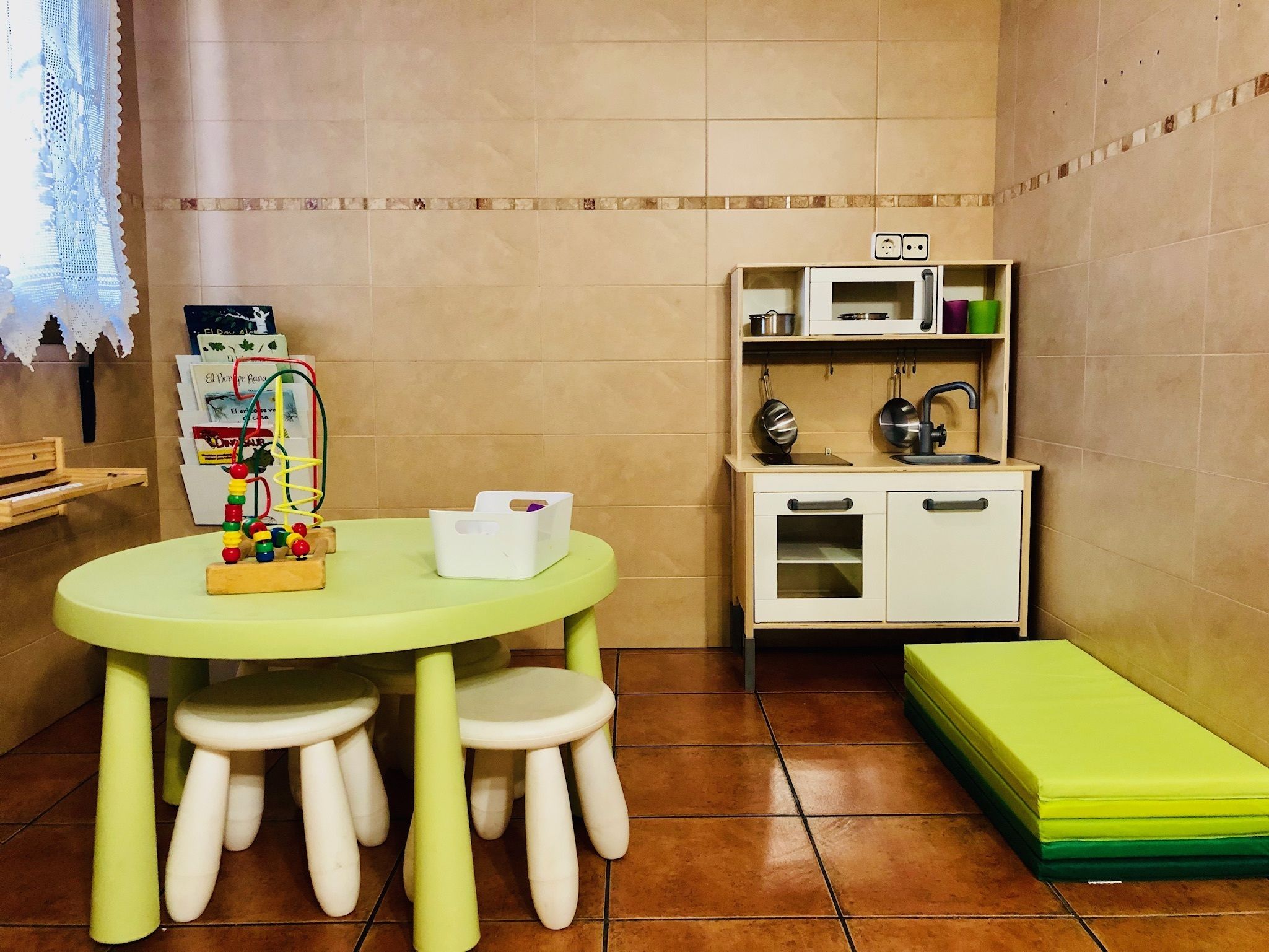 Una cocina compacta con una mesa redonda, taburetes, microondas, lavabo y un pequeño armario.