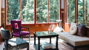 A spacious room with large windows, a chandelier, a sofa, a chair, and a coffee table.