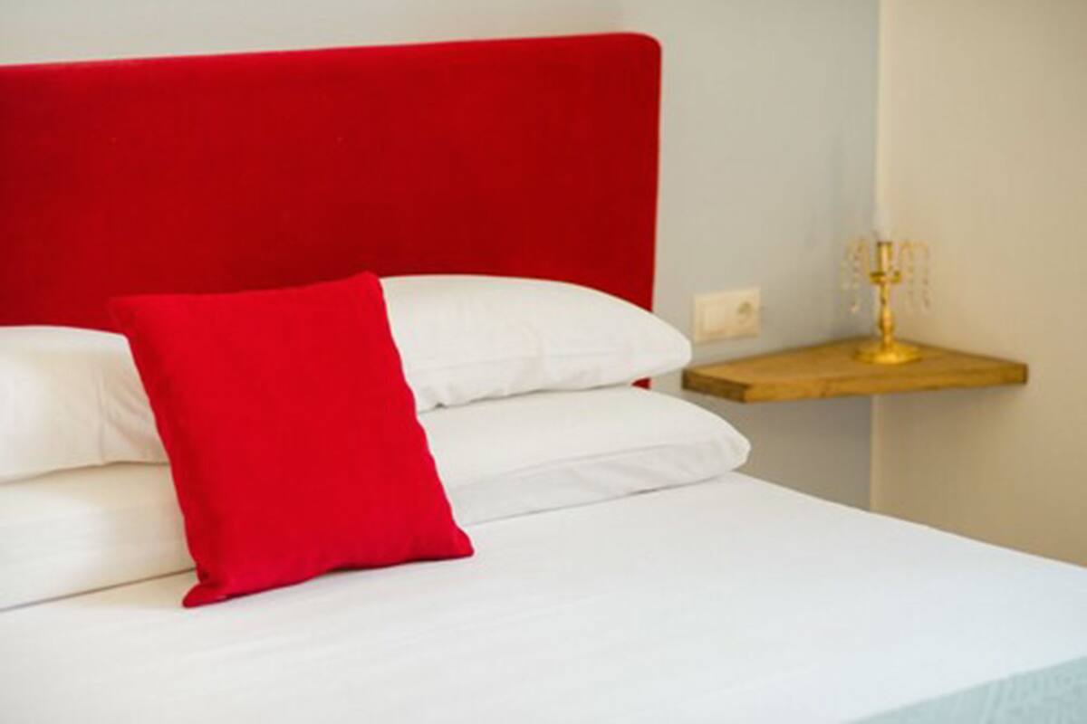 A bed with white bedding and a red headboard.