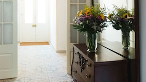 An interior with a wooden dresser, a mirror, and a vase with flowers.