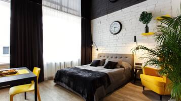 Una camera da letto moderna con un letto, una scrivania e una sedia. Ci sono degli orologi appesi al muro e una pianta su uno scaffale.
