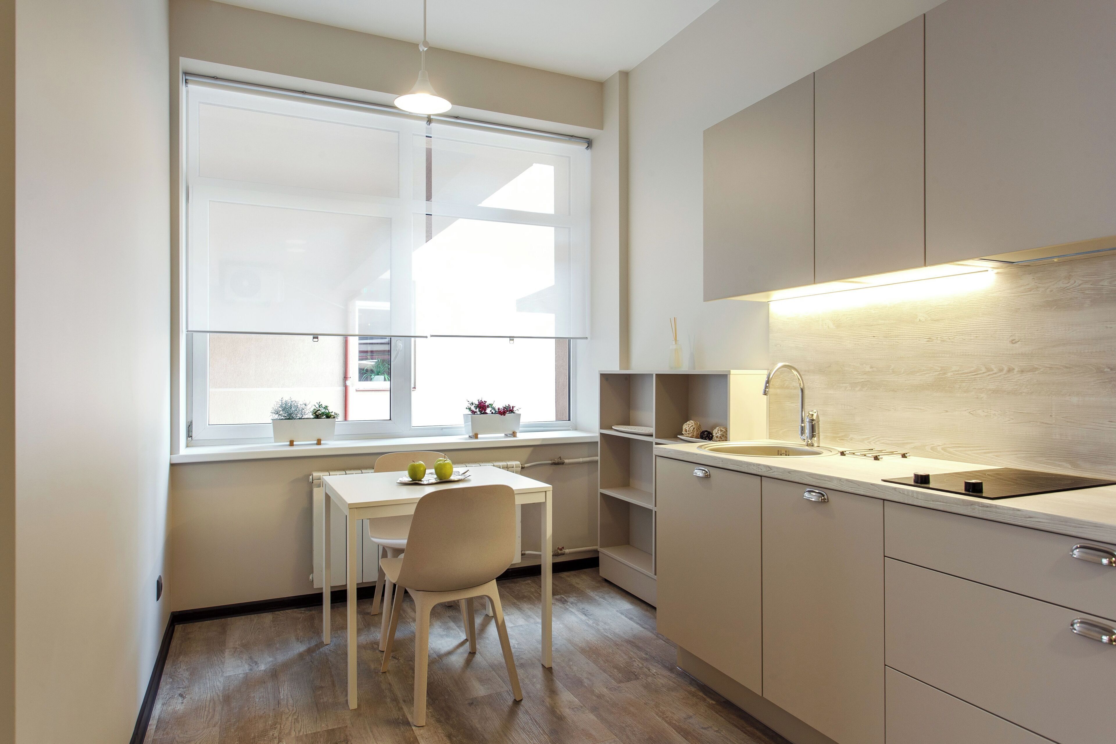Una cocina compacta con ventana, una mesa de comedor y un lavabo.