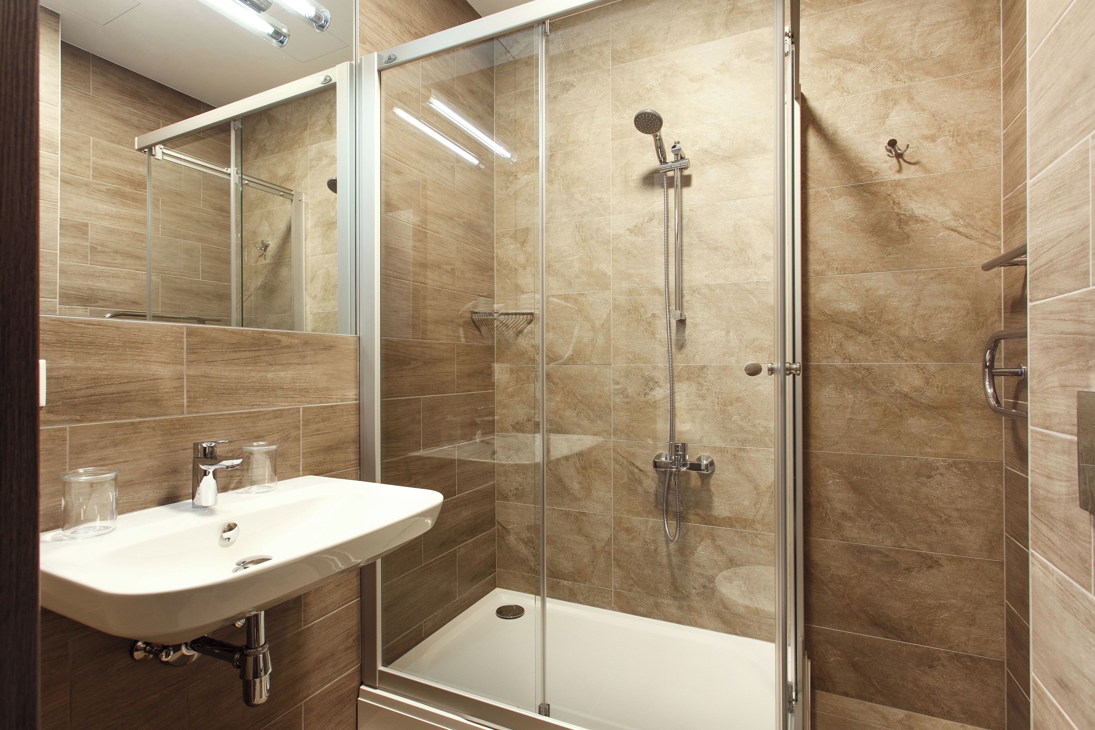 A modern bathroom with a glass-enclosed shower, a sink, and a mirror.