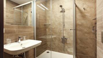 A modern bathroom with a glass-enclosed shower, a sink, and a mirror.