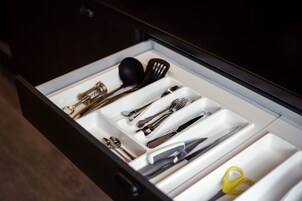 Un cajón con utensilios de cocina ordenados, incluyendo cucharas, tenedores, cuchillos y un par de tijeras.